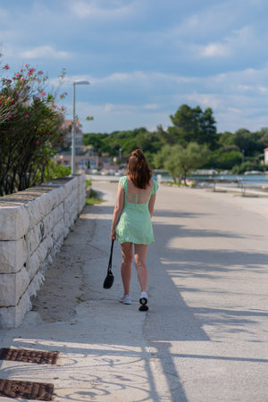 A girl in a green short dress walks along the promenade of a resort village in Croatia.の写真素材