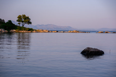 Gulf of the Adriatic Sea, beautiful view from the beach. Green pine trees, moored rocks and calm waters. Burn the forest in the background.の写真素材
