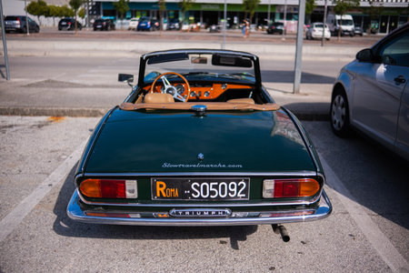 Ancona, Italy - 16 Sep 2023: An old vintage perfectly restored Triumph car is parked on the street on a sunny summer day. Green old Triumph roadster on a flowery street.のeditorial素材