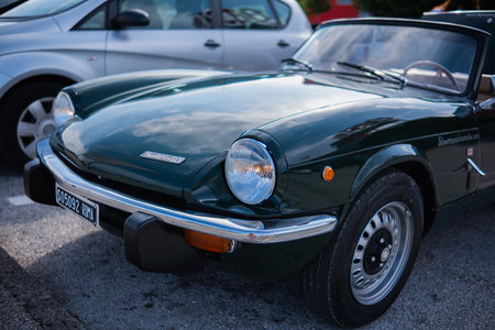 Ancona, Italy - 16 Sep 2023: An old vintage perfectly restored Triumph car is parked on the street on a sunny summer day. Green old Triumph roadster on a flowery street.のeditorial素材