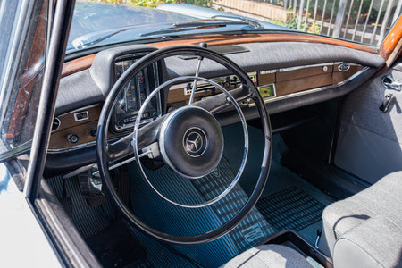 An old vintage perfectly restored Mercedes car is parked on the street on a sunny summer day. Blue old Mercedes on a flowery street.のeditorial素材