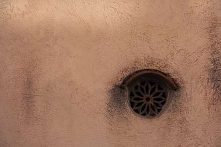 Vintage ventilation hole in the wall. Minimalistic photo. The wall is covered in dust and soot around the ventilation hole.の写真素材