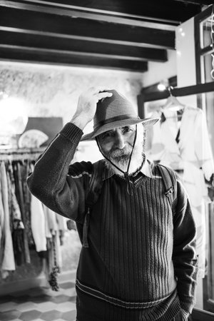 Bearded Old Man in a Hat. An old traveler with a backpack and a beautiful hat. Black and White Portrait of a Handsome Old Man.の写真素材