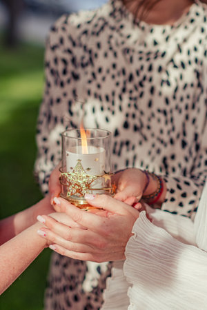 Three women are holding a glass glass with candles in their hands. Women's meeting, practice, esotericism. Burning candle in female hands.の写真素材