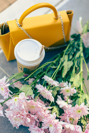 Chrysanthemum flowers, women's yellow bag and a glass of coffee. Urban still life. Urban photo.の写真素材