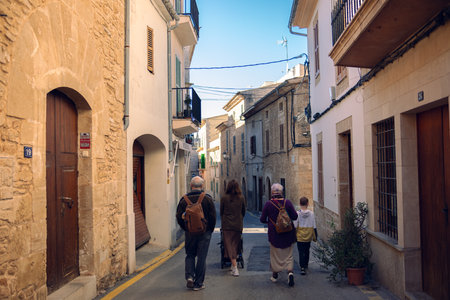 A large family walks along the street of the old city. Grandmother, grandfather, their children and grandchildren on the narrow street. Tourists travel with the whole family around Europe.の写真素材