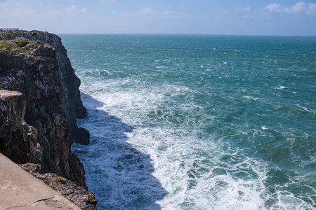 Beautiful view of the raging ocean. High steep coastal cliffs, white ocean foam and high waves.の写真素材