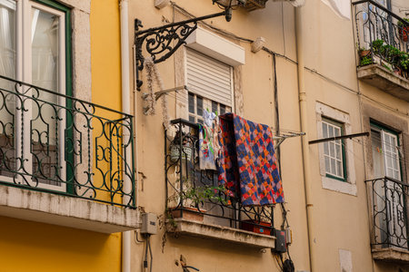Street of Lisbon city. Washed clothes hang from the balcony and dry outside. Clothes dry on the balcony, old vintage houses, authentic architecture.の写真素材