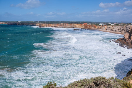 Beautiful view of the raging ocean. High steep coastal cliffs, white ocean foam and high waves.の写真素材