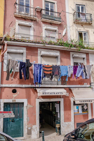 Street of Lisbon city. Washed clothes hang from the balcony and dry outside. Clothes dry on the balcony, old vintage houses, authentic architecture.の写真素材