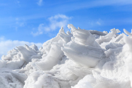 Mound of snow and ice on a background of blue sky with cloudsの写真素材