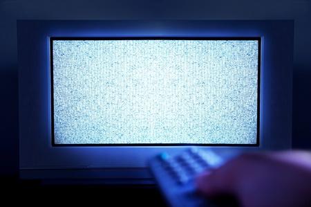 Someone holds a tv remote control late at night and tries to find a tv show to fight insomniaの写真素材