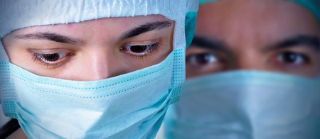 Closeup portrait of two surgeons during a surgery. Blue cast and vignetting applied. の写真素材