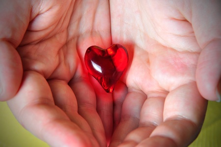 Glowing red heart hold on the palm of oneの写真素材