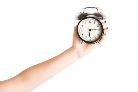Female hand holding an alarm clock ringing isolated in white