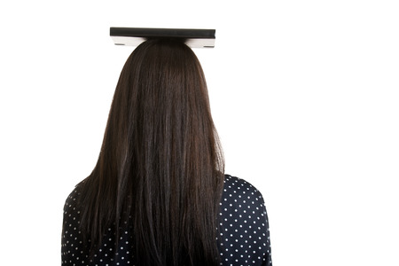 Woman holding a book over her head to show the concept of elegance, viewed from the back, isolated...