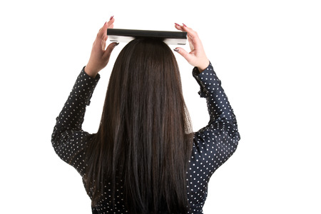 Woman holding a book over her head to show the concept of elegance, viewed from the back, isolated in whiteの写真素材
