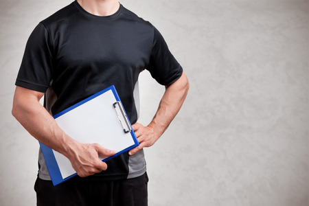 Personal Trainer, with a pad in his hand, isolated in greyの写真素材