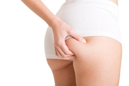 Closeup of woman examining her buttocks looking dor cellulite, isolated in whiteの写真素材