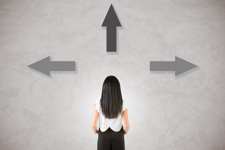 Backside of a businesswoman with arrows around her, isolated in grey