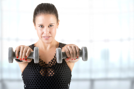 Woman working out with dumbbells at a gym, in a gymの写真素材