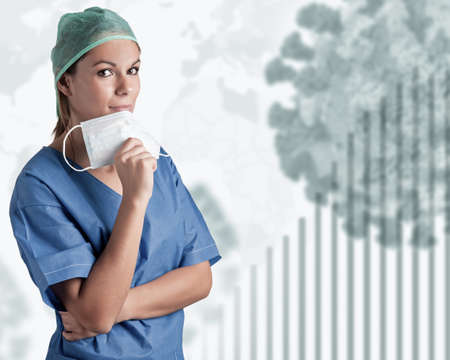 Young female doctor with scrubs, holding a face mask during the coronavirus pandemicの写真素材