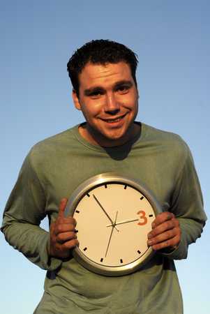 young man with a clock at sunset light