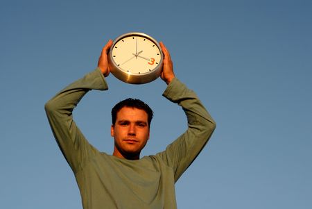 young man with a clock at sunset lightの写真素材