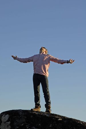 young man with arms wide open and the sky as backgroundの写真素材