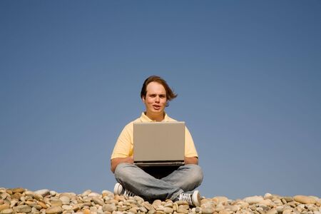young casual man with laptop at the beachの写真素材