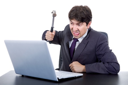 young crazy business man with a hammer smashing a laptopの写真素材