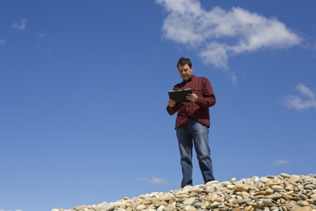 Young casual man working with touch pad at the beachの写真素材