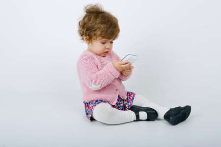 young baby with a phone on a grey backgroundの写真素材