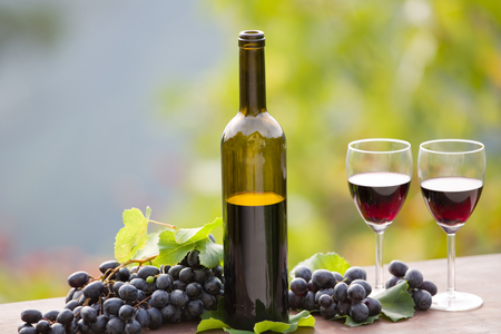 wine bottle and grapes on wooden table outdoorの写真素材