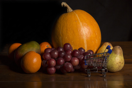 variety of fruits and a small shopping cart on a woden table, studio pictureの写真素材