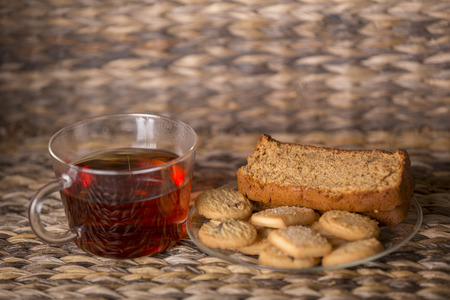 Tea, cookies and cake on wooden table in front of a wooden background