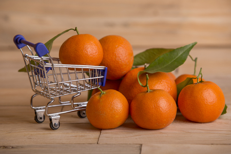 fresh tangerines and a shopping cart on a wooden tableの写真素材