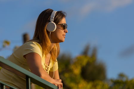 beautiful casual woman enjoying music at the sunset, with headphones, outdoorの写真素材