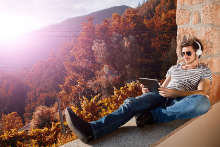 young man listening music with headphones, outdoorの写真素材