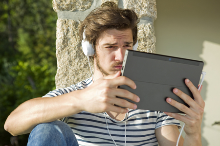 young man listening music with headphones, outdoorの写真素材