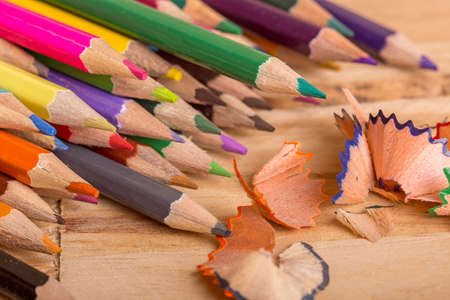 Wooden colorful pencils with sharpening shavings, on wooden tableの写真素材