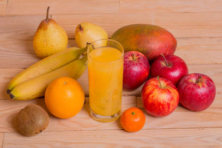 variety of fruits and orange juice on a wooden table, studio pictureの写真素材