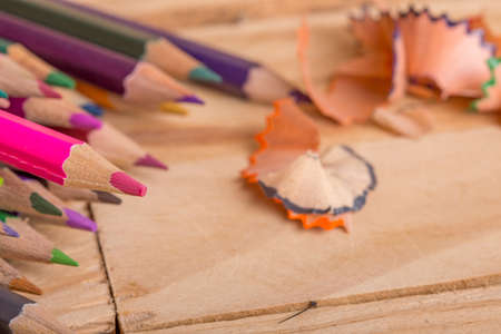Wooden colorful pencils with sharpening shavings, on wooden tableの写真素材