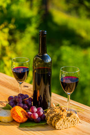 wine bottle, grapes, cheese and bread, on wooden table, outdoorの写真素材