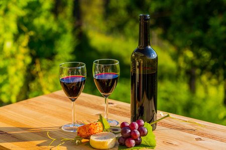 wine bottle, grapes, cheese and bread, on wooden table, outdoorの写真素材