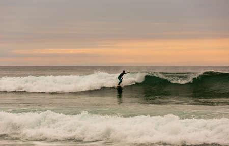 LA VEGA, ASTURIAS, SPAIN: Surfers on the beach of La Vega, at dusk, near Llanes, Asturias, Spainのeditorial素材