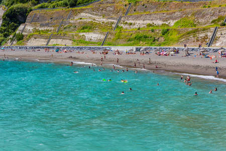 Ribeira Quente, Sao Miguel island, Azores, Portugal: People swimming in the sea and relaxing on a nice sandy beach Praia do Fogo by the town Ribeira Quente.のeditorial素材