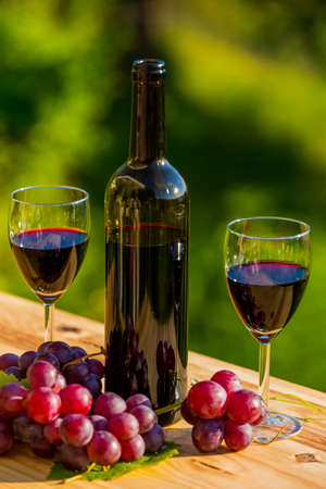 wine bottle and grapes on wooden table, outdoorの写真素材