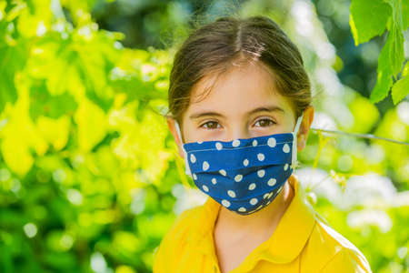 Little girl with mask against corona virus covid outdoorの写真素材
