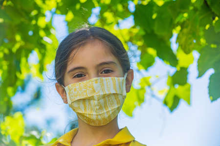Little girl with mask against corona virus covid outdoorの写真素材